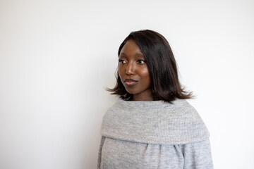 Fototapeta premium A confident woman with shoulder-length hair wearing a gray sweater, posing against a white background.