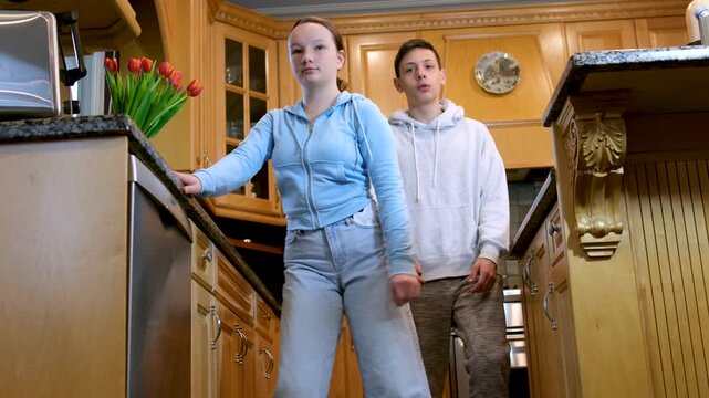 Cleaning the kitchen teenagers. Dishwasher. Brother and sister at home cleaning the kitchen helping each other keep order