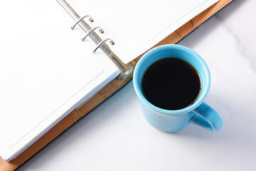 コーヒーを飲みながら、システム手帳でデスクワークをしているイメージ
