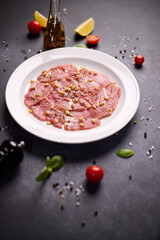 cooking tuna carpaccio - Fresh raw tuna fillet with olive oil and pine nuts on white ceramic plate