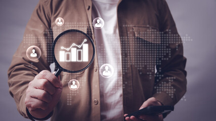 Man holding magnifying glass and looking at world map and businessman with growth graph icon in...