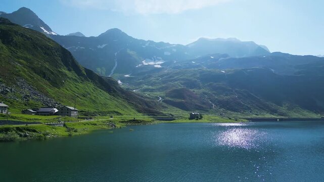 A stunning drone view over the Spl&uuml;gen Pass, capturing crystal-clear alpine lakes surrounded by towering mountains. The serene landscape showcases nature's beauty at the border of Switzerland Italy