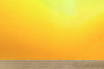 木製の机の上を光が照らす明るいオレンジ色の背景