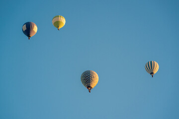 Obraz premium Hot air balloons in dark blue, red and yellow colors flying in a slightly cloudy blue sky
