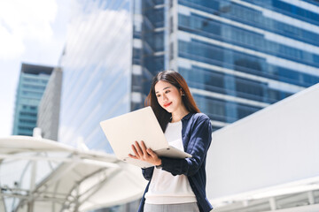 Business freelance adult asian woman using laptop standing on day building background