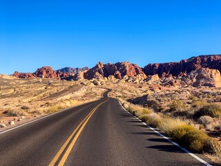Open desert road through a rocky landscape under a clear blue sky