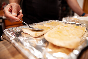 Close-up of a person spreading butter on bread slices using a spoon