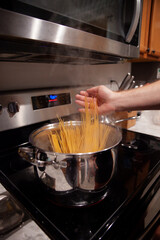 Uncooked spaghetti going into a pot of boiling water on the stove