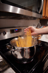 Placing spaghetti into a pot of boiling water
