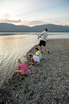 Father and kids skipping rocks at a beach