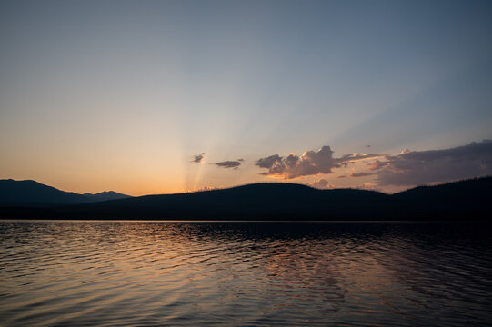 Serene Sunset Over Calm Lake With Mountain Silhouette