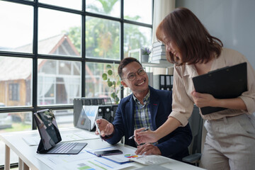Analysis. Conversation. Team of Asian businessmen or office workers pointing at financial data documents. Calculating income. Business information on files and laptops. Operation plan teamwork.