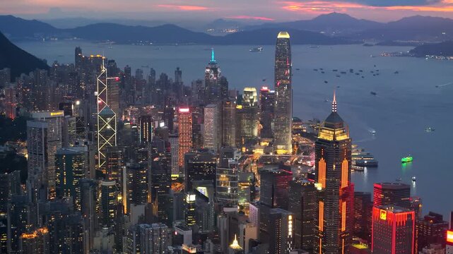 Aerial view drone video City landscape of the famous travel landmark cityscape. buildings with light and transportation at Victoria Harbour skyline and Kowloon at sunset along Hong Kong Island China.