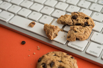 Broken chocolate chip cookies on keyboard computer background. Cookies website internet homepage...