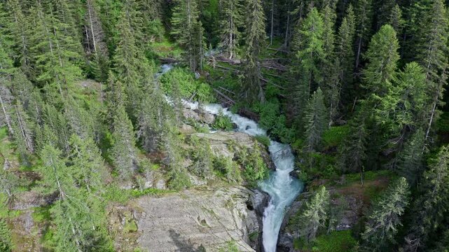 Cascate del rutor waterfall flowing through a lush green forest, aerial view