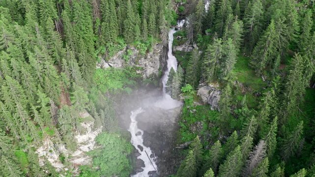 Cascate del rutor waterfall surrounded by dense green forest in summer, aerial view