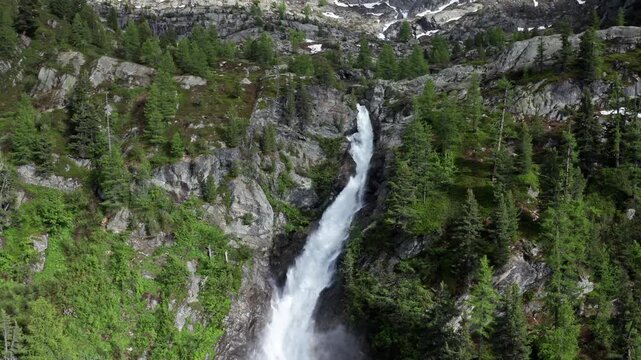Cascate del rutor waterfall cascading through lush green mountains in summer, aerial view