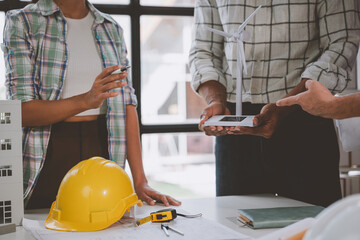 A skilled team of engineers work together in a meeting. Draft blueprints for condos, apartments and houses, wind turbines, real estate investment construction, agreements, agents, leases.