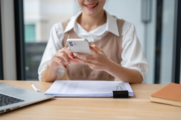 Fototapeta premium A cropped image of a beautiful Asian businesswoman using her smartphone at her desk in the office.