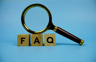 FAQ with wooden blocks alphabet letters and Magnifying glass on blue background