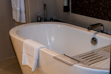 Modern minimalist bathroom interior, modern bathroom cabinet, white sink, wooden vanity, interior plants, bathroom accessories, bathtub and shower, white and beige walls, concrete floor.