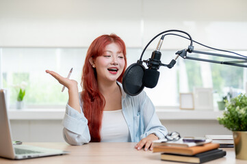 A charming Asian female podcaster is speaking into a microphone, recording her podcast in the studio