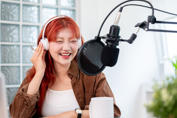 A cheerful Asian female podcaster is enjoying conducting her podcast in the studio.