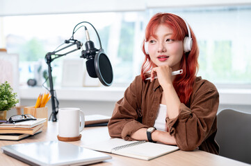 A thoughtful Asian female podcaster is listening to her guest during a remote interview.