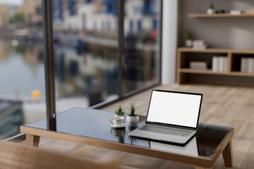 A laptop computer mockup on a coffee table in a contemporary minimalist apartment.