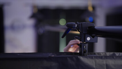 Person mounting light tube on pole between walls on video production set close-up