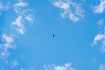 Airplane glides through clear sky, lone airplane. Single-engine airplane soaring through clear blue sky, surrounded by wispy clouds, freedom and adventure, tranquility of flying at high altitudes.