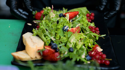 The process of preparing a salad of chicken, vegetables, herbs and fruits