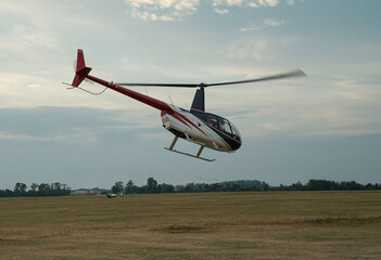 lecący helikopter nad płytą lotniska o zachodzie słońca na tle nieba © siwyk