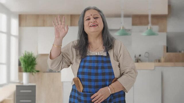 Happy Indian aged housewife saying Hello and waving