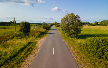 Fototapeta premium Drone view of the highway road, forest and fields, top view and blue sky