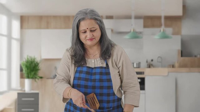 Disgusted Indian aged housewife cooking food