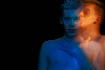 blurred silhouette, young man posing in the dark with red and blue light in the studio