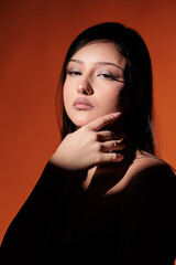 Brunette girl posing in a beam of light in the studio, on a red background, light and darkness.