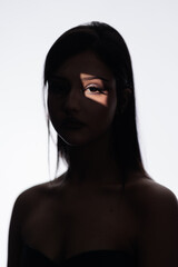 Fototapeta premium Brunette girl posing in a beam of light in the studio, light and darkness.