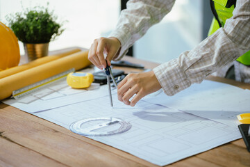 Concept architects or engineer holding pen pointing equipment architects on the desk with a blueprint in the office.