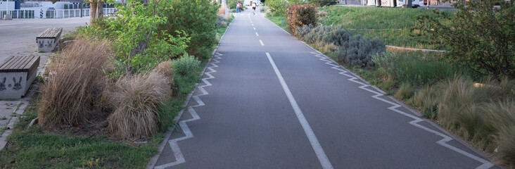 A road with a white line down the middle and a green area on the side