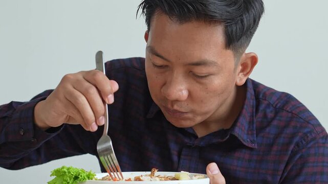 Happy Asian Man Eating Chicken Steak With Fork