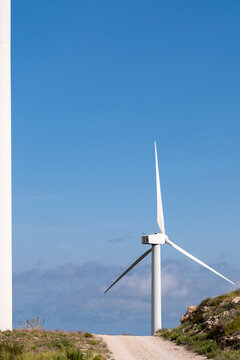 A wind turbine stands prominently near a modest hill under a clear blue sky, symbolizing renewable energy and the harnessing of wind power for sustainable electricity generation in Tarragona Spain