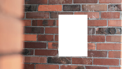 Blank white poster taped on red brick wall partially obstructed by another brick structure on left....