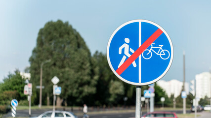 No pedestrian or bicycle sign on street with blurred urban background. Sign is blue with red...