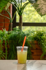 Yellow cold soft drink in a plastic cup with a straw in a cafe. Bubble tea. Selective focus