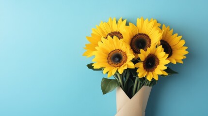 Obraz premium A bunch of sunflowers in vibrant yellow, their detailed petals shining, set against a pale blue background and wrapped in elegant craft paper.