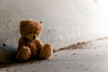 Homeless poor teddy bear in a dark tunnel. Homelessness, poverty, depression concept. Light in the...