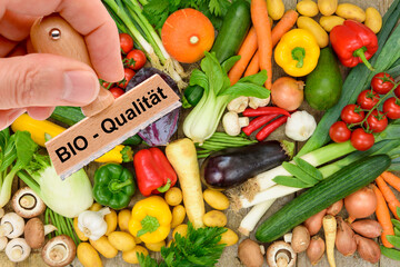 Ein Holzstempel ist beschriftet mit dem Aufdruck: Bio-Qualität über frischem Obst und Gemüse - FOTOMONTAGE