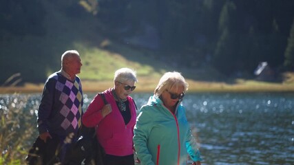Two Senior Caucasian Women and a Man Exploring Nature Together and Walking by a Lake. Concept of friendship, companionship, active aging, outdoor activity, vitality, retirement